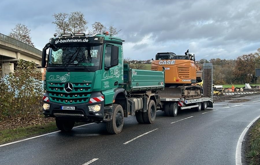 Lkw mit transportierter Baumaschine auf einer Straße