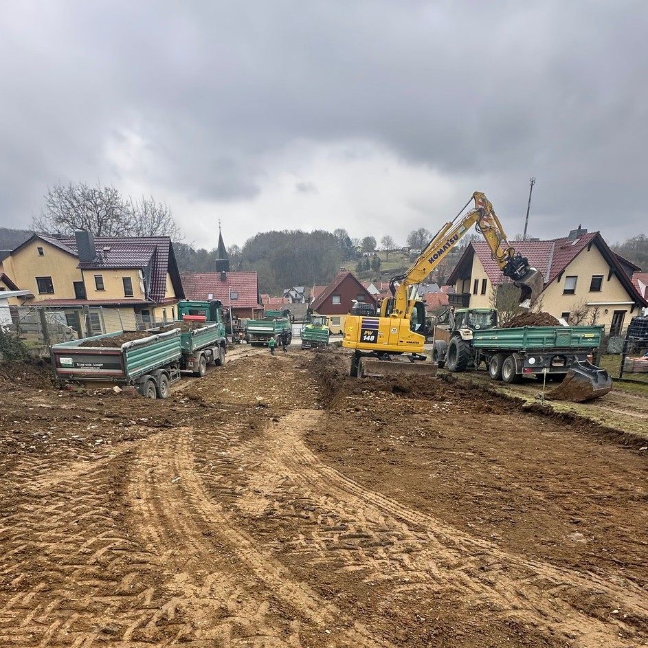 Bagger und mehrere Transportfahrzeuge bei Erdarbeiten im Wohngebiet