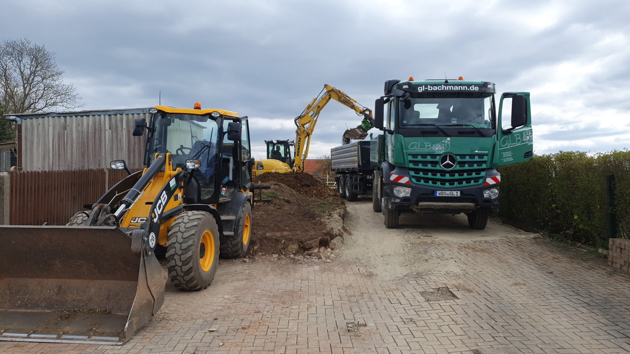 Lkw und Radlader beim Materialtransport auf einer Baustelle